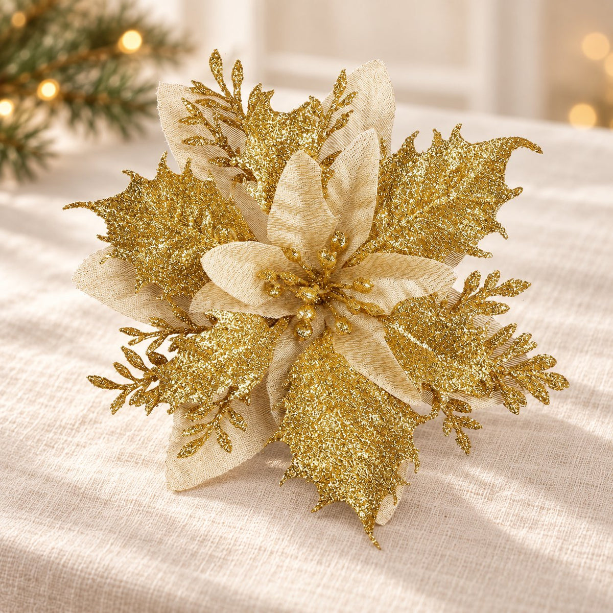 Fleur de Noël Éclat dorée, 14 cm, mise en scène sur lin ivoire