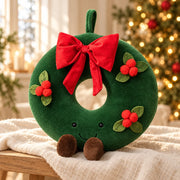 Peluche de Noël couronne verte à nœud rouge, petites baies et pieds bruns, dans un décor doux