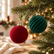 Détail de deux boules effet velours rouge et vert dans les branches d’un sapin