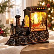Train de Noël lumineux à finition bronze patiné, décor de cerf dans une forêt enneigée