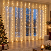 Rideau LED blanc chaud devant une baie vitrée, dans un salon de Noël aux tons ivoire et bordeaux